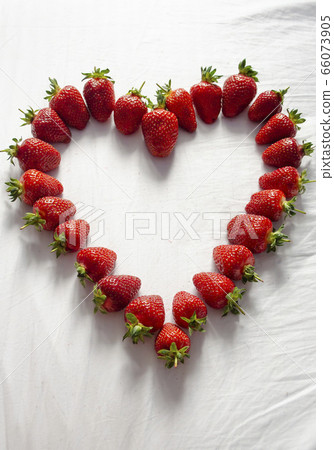 Ripe strawberries are laid out on a white background in the shape of a heart 66073905