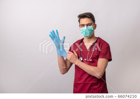 Young volunteer puts surgical gloves. 66074210