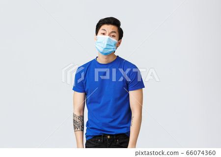 Different emotions, social distancing, self-quarantine on coronavirus and lifestyle concept. Tired and bored asian man in medical mask, guy dying of boredom staying home during covid-19 66074360