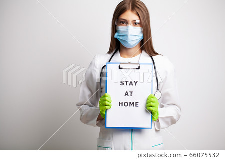 Woman in mask holding blank with inscription stay at home calling for stop spreading covid-19. 66075532