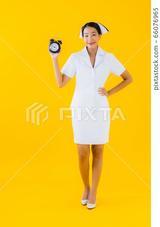 Portrait beautiful young asian woman thai nurse show clock or alarm Portrait beautiful young asian woman thai nurse show clock or alarm 66076965