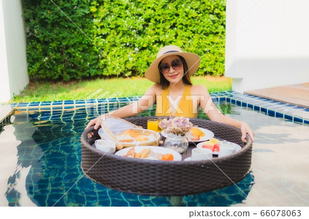 Portrait beautiful young asian woman happy smile relax with breakfast floating around swimming pool 66078063