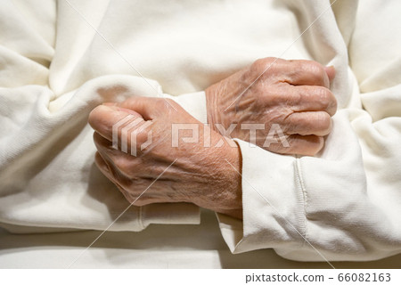 Hands of an elderly woman clenched in fists on her Hands of an elderly woman clenched in fists on her 66082163