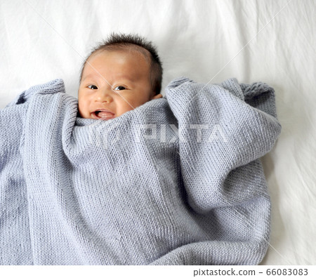 Cute happy baby new born lying on a blue knitted 66083083