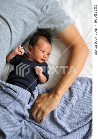 Father with his newborn baby son lying in bed. Father with his newborn baby son lying in bed. 66083103