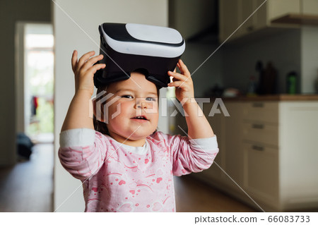 Toddler girl with vr glasses at home. Learning, watching movie, playing games. Future technologies Toddler girl with vr glasses at home. Learning, watching movie, playing games. Future technologies 66083733