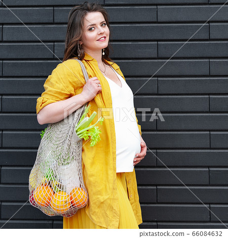 Pregnant woman in yellow clothes with an eco bag Pregnant woman in yellow clothes with an eco bag 66084632