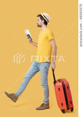 Man in hat and jeans with ticket and suitcase. 66085070