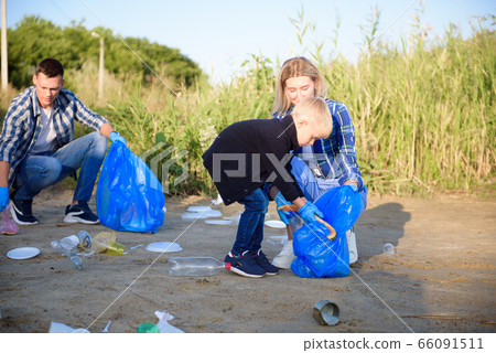 Volunteer man collecting trash on the beach. Volunteer man collecting trash on the beach. 66091511