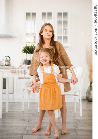 Two sisters play in a bright, stylish kitchen. Beautiful interior. Two sisters play in a bright, stylish kitchen. Beautiful interior. 66093296