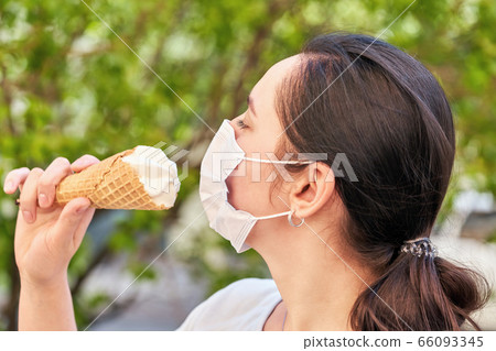 Girl in medical mask keeps ice cream in a waffle 66093345