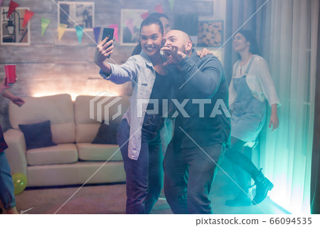 Man and beautiful woman using smartphone taking a selfie Man and beautiful woman using smartphone taking a selfie 66094535