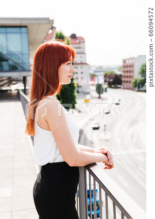 Girl stands near office center and looks sideways Girl stands near office center and looks sideways 66094572