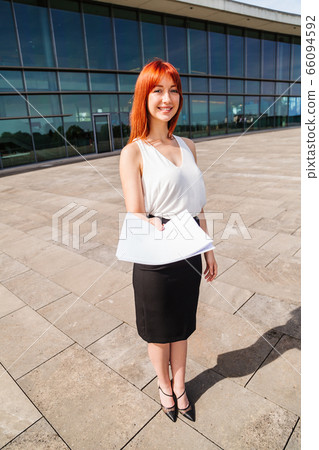 Young redhead business woman in formal outside Young redhead business woman in formal outside 66094592