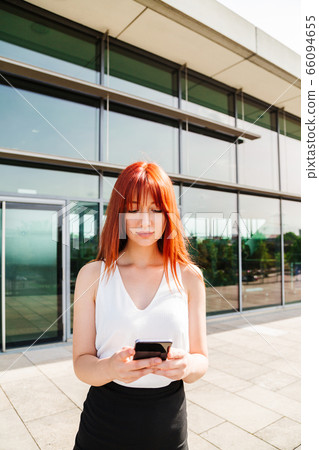 Portrait of red-haired girl using her mobile phone 66094655