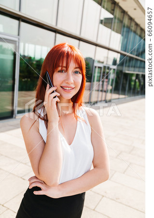 Young woman talking on mobile phone near building Young woman talking on mobile phone near building 66094657