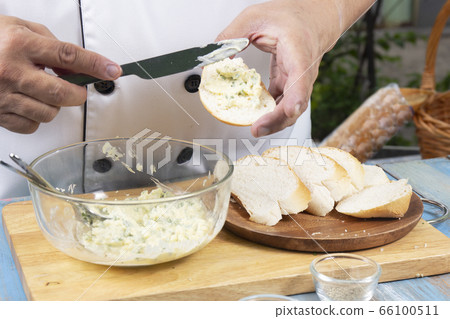 Chef spread garlic butter on slice bread / 66100511
