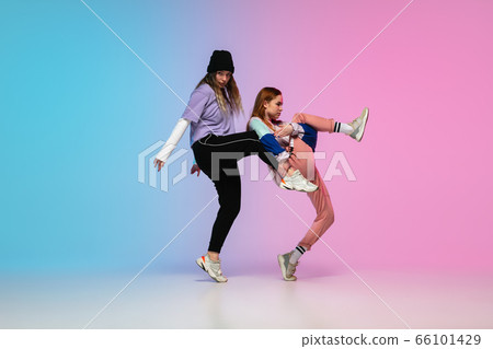 Girls dancing hip-hop in stylish clothes on gradient background at dance hall in neon light. Girls dancing hip-hop in stylish clothes on gradient background at dance hall in neon light. 66101429