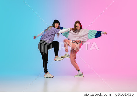 Girls dancing hip-hop in stylish clothes on gradient background at dance hall in neon light. 66101430