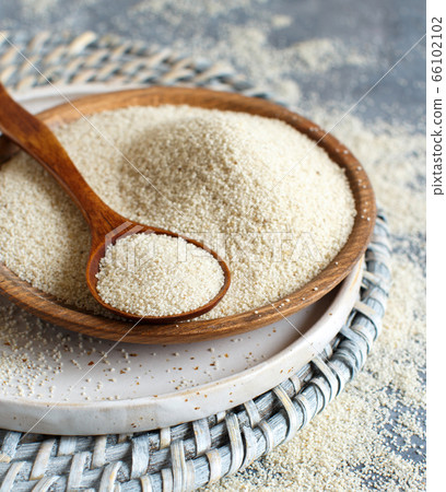 Raw uncooked fonio seeds with a spoon on a plate Raw uncooked fonio seeds with a spoon on a plate 66102102
