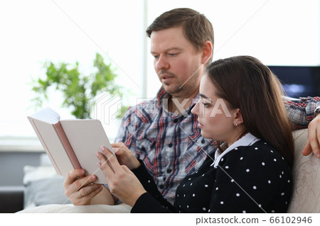 Couple sitting at home and reading book together 66102946