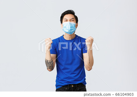 Different emotions, social distancing, self-quarantine on covid-19 and lifestyle concept. Rejoicing enthusiastic asian guy winning, celebrate victory, triumphing with medical mask on, fist pump 66104903