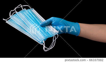 Doctor's hand in medical gloves holding a pile of masks isolated on black Doctor's hand in medical gloves holding a pile of masks isolated on black 66107882