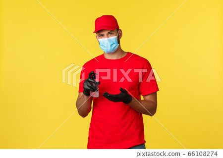 Covid-19, delivery orders, shopping, contactless handling and social distancing concept. Courier in red uniform, medical mask and gloves, apply hand sanitizer to prevent catching coronavirus Covid-19, delivery orders, shopping, contactless handling and social distancing concept. Courier in red uniform, medical mask and gloves, apply hand sanitizer to prevent catching coronavirus 66108274