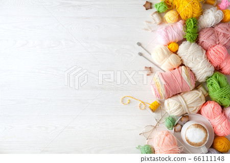 Woolen and cotton bright yarn lies in a basket. Glasses lie on a white wooden background. 66111148