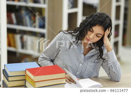 Latin girl preparing for examination in library 66111477