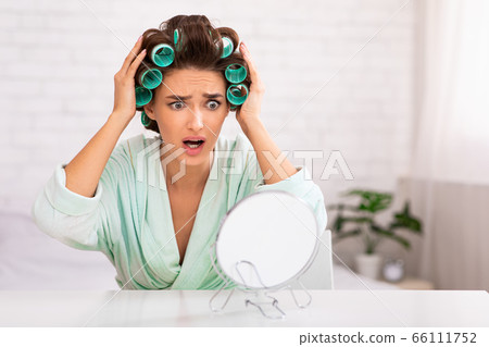 Unhappy Woman Touching Hair Curling It Sitting At Home 66111752