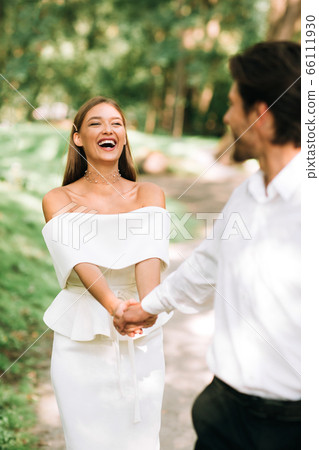 Happy Wedding Couple Walking Holding Hands Outdoors In Nature Park Happy Wedding Couple Walking Holding Hands Outdoors In Nature Park 66111930