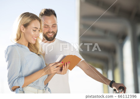 Travel concept. Loving couple checking tickets near airport Travel concept. Loving couple checking tickets near airport 66112396