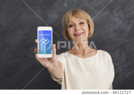 E-Payment. Smiling mature woman holding smartphone with opened app for online banking E-Payment. Smiling mature woman holding smartphone with opened app for online banking 66112727