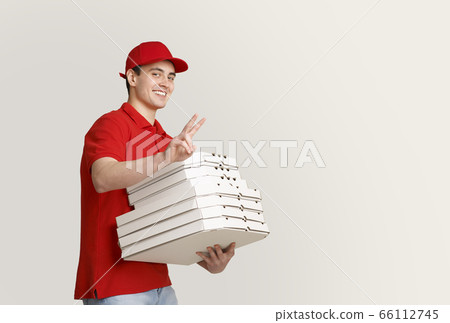 A lot of pizza to home. Smiling courier shows peace sign and holds many boxes A lot of pizza to home. Smiling courier shows peace sign and holds many boxes 66112745
