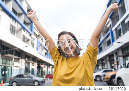 woman wearing face shield standing in the street, COVID- 19 66117020