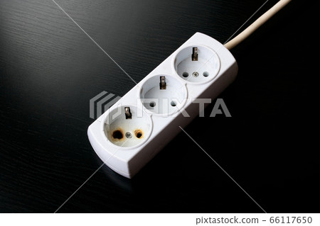 Old burnt extension cord on a black background 66117650
