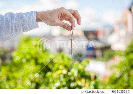 man holding key to the house on background of houses in the city. Deal with the real estate concept 66120985