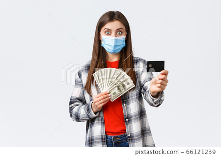 Money transfer, investment, covid-19 pandemic and working from home concept. Surprised young woman showing credit card and holding her cash savings, make bank account to save-up for trip 66121239