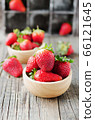 red ripe strawberry in a wooden bowl on a rustic 66121645