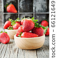 red ripe strawberry in a wooden bowl on a rustic 66121649