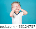 Two year old curly baby girl covers her face with 66124737