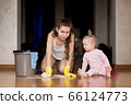 A disgruntled mother launders the floor with her hands. Near sits her daughter 66124773