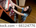 Girl hides a small stack of euro banknotes in clothes in a wardrobe 66124776