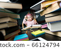 A little student sits at a table that is littered with educational materials 66124794