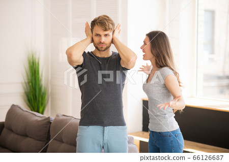 Young bearded man closing his ears while his wife shouting Young bearded man closing his ears while his wife shouting 66126687