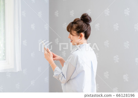 A woman looking at the smartphone with her back facing here (side profile) A woman looking at the smartphone with her back facing here (side profile) 66128196