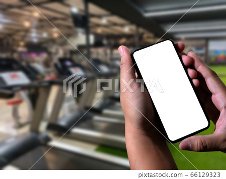 Young man Hand holding smartphone in gym to 66129323