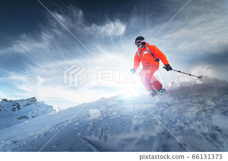 Skier rides on a snowy slope on a sunny day at sunset against the backdrop of the mountains. The concept of winter skiing 66131373
