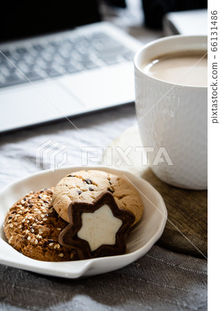 Real home workplace, laptop with cup of coffee with cookies on bed with cozy blanket 66131486